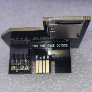 Close-up of a black electronic adapter with gold contacts and labeled pins.